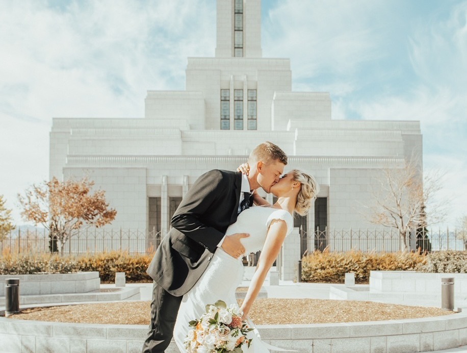 A bride and groom kissing on the grounds of a Latter-day Saint temple